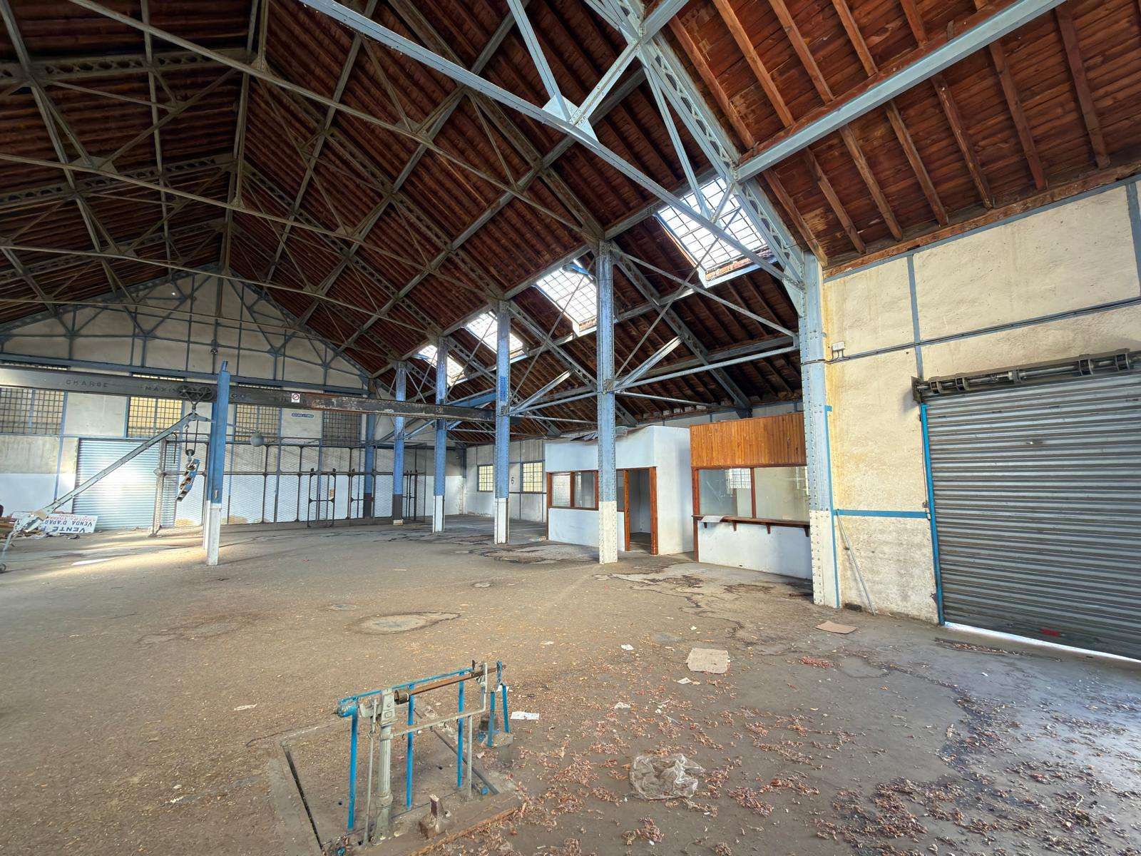 Intérieur de la Halle Subra, hauteur sous plafond, trusses bleus et lucarnes
